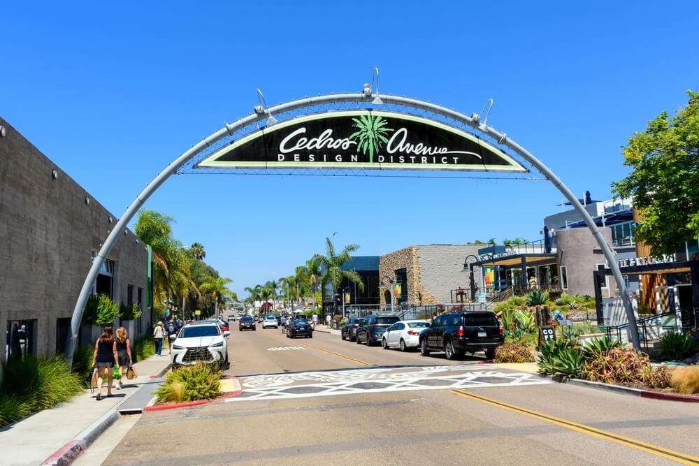 Street view of the Cedros Avenue Design District archway with cars and pedestrians in Solana Beach, California, highlighting when to Update Car Insurance After Moving California.