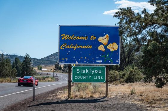 Welcome to California” roadside sign at the Siskiyou County line along a rural highway, highlighting new car insurance rules in california.