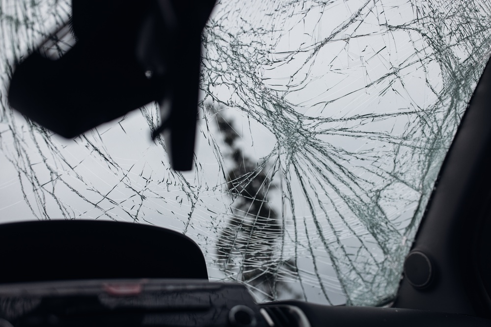 Cracked car windshield with extensive damage viewed from inside the vehicle.
