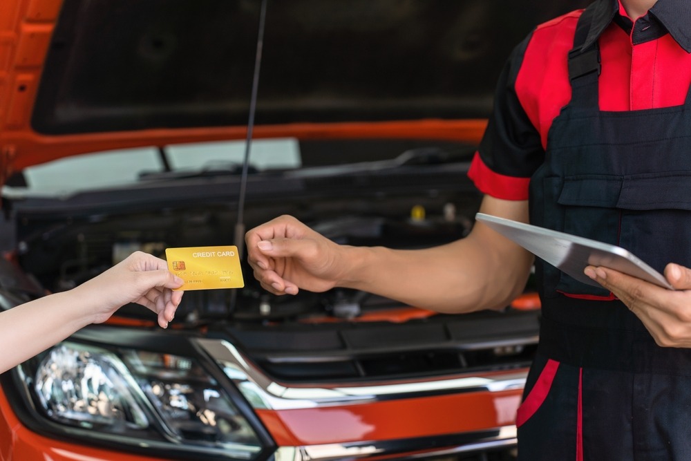 Customer hands a credit card to a mechanic during vehicle service and repair.