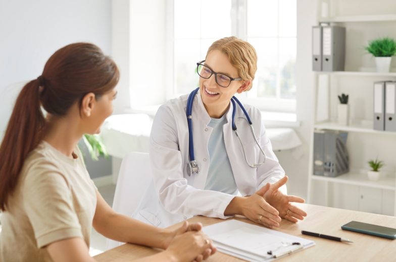 Woman discussing health insurance plans with a healthcare professional in a medical office.