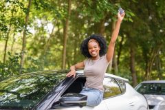 Mujer sonriente junto a su auto sosteniendo las llaves mientras conoce si el seguro GAP es reembolsable.