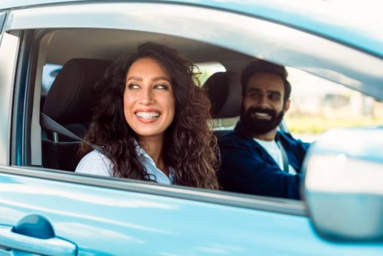 Pareja sonriente dentro de un auto, mostrando acceso a seguros de autos para hispanos en EE. UU.