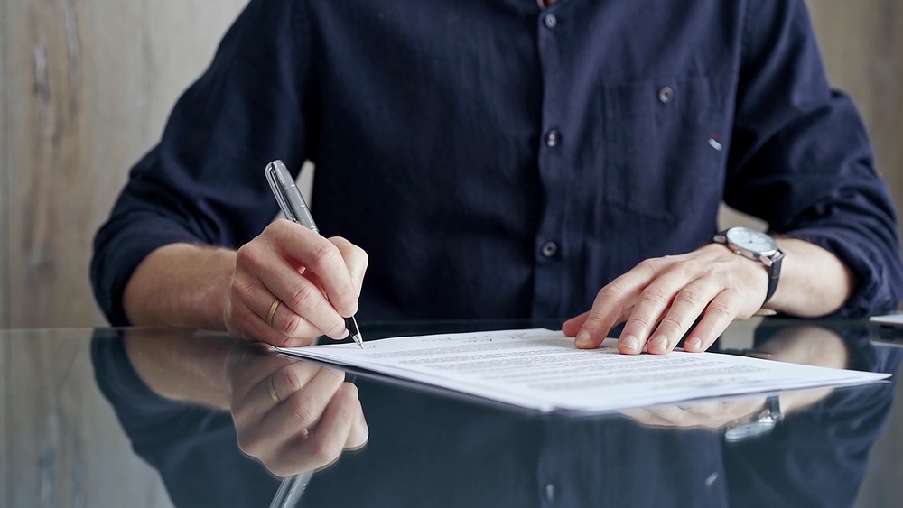Persona firmando documentos relacionados con un seguro GAP reembolsable.