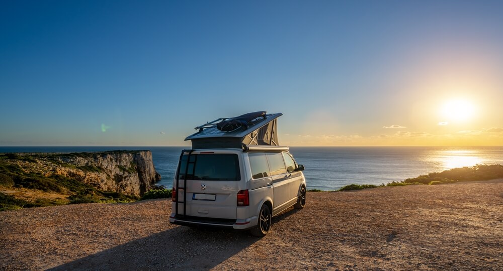 Van para acampar estacionada frente al océano durante el atardecer en un destino de California cerca de San Diego y Los Ángeles.