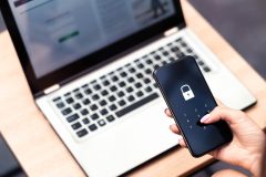 Seguridad digital en smartphone con bloqueo de acceso frente a una computadora portátil.