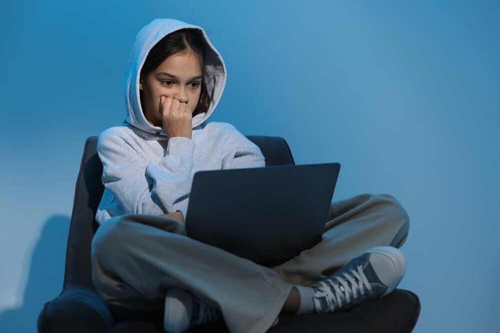 Joven preocupada frente a una laptop por posibles riesgos de seguridad digital.