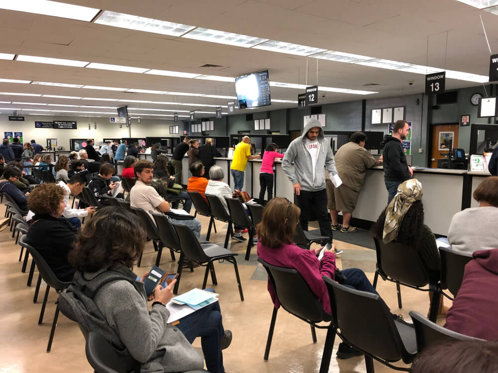 Personas esperando en el DMV de California para trámites de registro y sticker de carro.