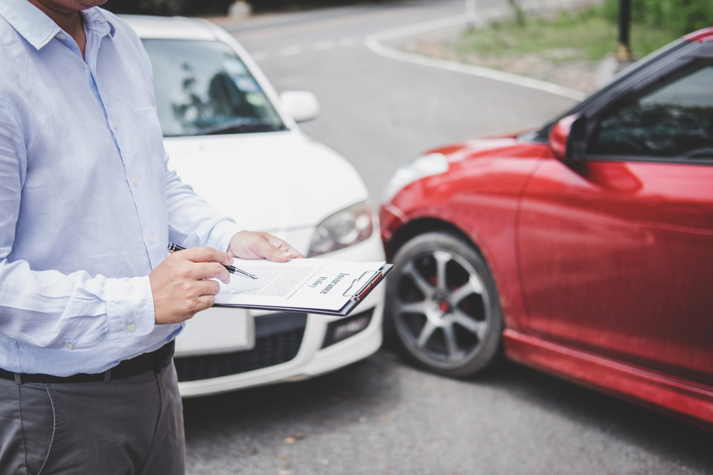 Ajustador revisando detalles porque un conductor va a reclamar a un seguro de coche