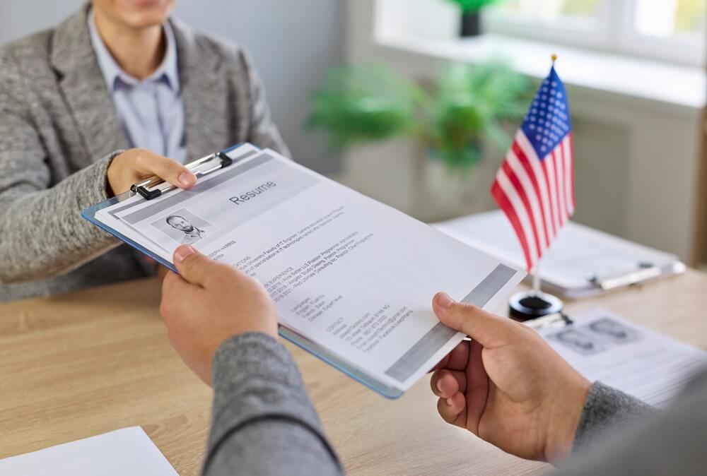 Persona entregando un currículum durante una entrevista laboral en Estados Unidos, relacionado con la solicitud de permiso de trabajo y oportunidades de empleo.