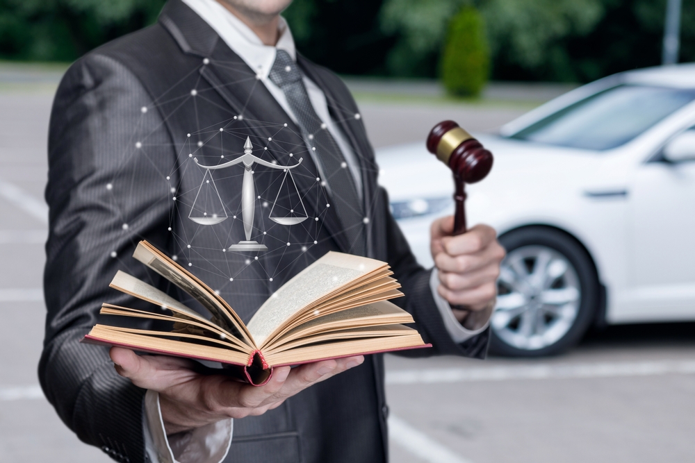 Hombre sosteniendo un mazo y un libro frente a un auto representando las nuevas leyes en California para conductores 