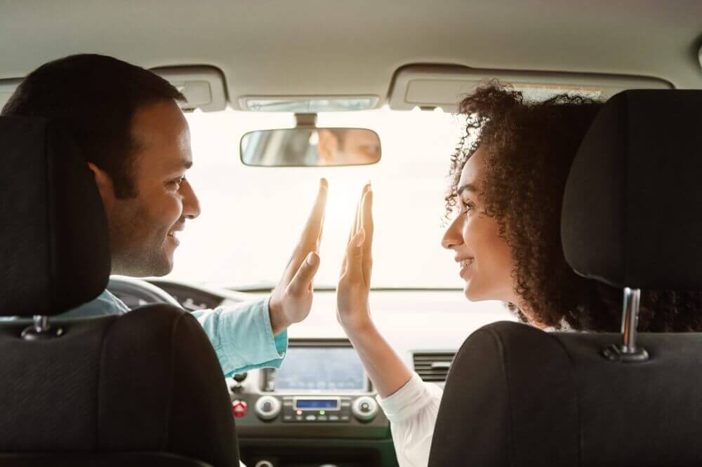 Dos familiares celebrando dentro de un automóvil después de completar la transferencia de un auto a un familiar.