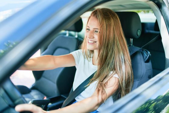 Mujer universitaria conduciendo un vehículo - Cómo elegir el mejor seguro de auto si eres estudiante en California - Cost-U-Less
