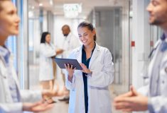 Doctora usando una tableta para gestionar al personal y los flujos de trabajo, ilustrando cómo las herramientas digitales apoyan la atención médica durante el Open Enrollment