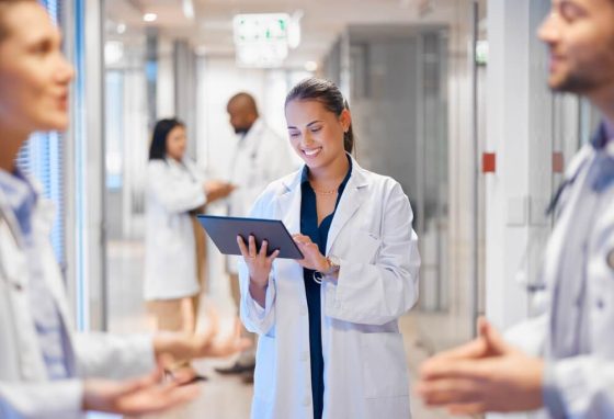 Doctora usando una tableta para gestionar al personal y los flujos de trabajo, ilustrando cómo las herramientas digitales apoyan la atención médica durante el Open Enrollment