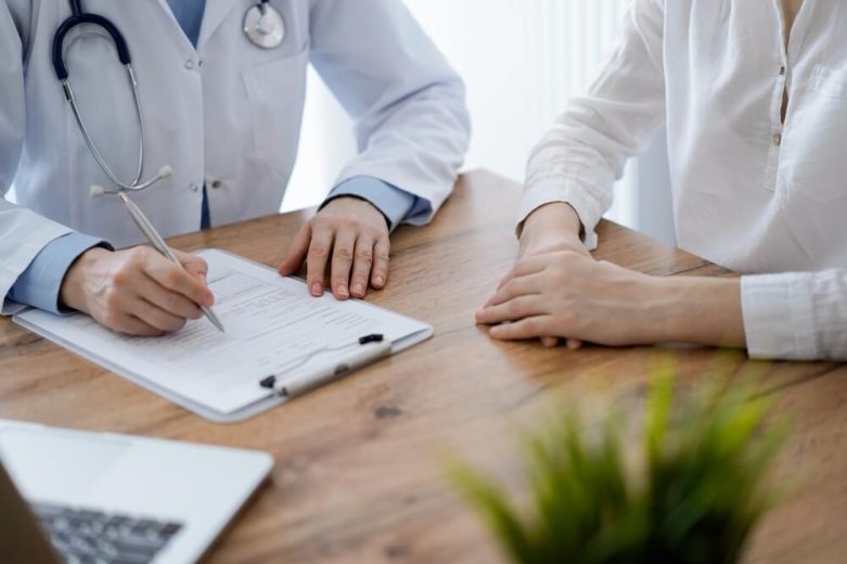 Médico revisando documentos médicos con un paciente durante una consulta, ilustrando qué pasa si no usas tu seguro de salud para atención preventiva y revisiones de rutina.
