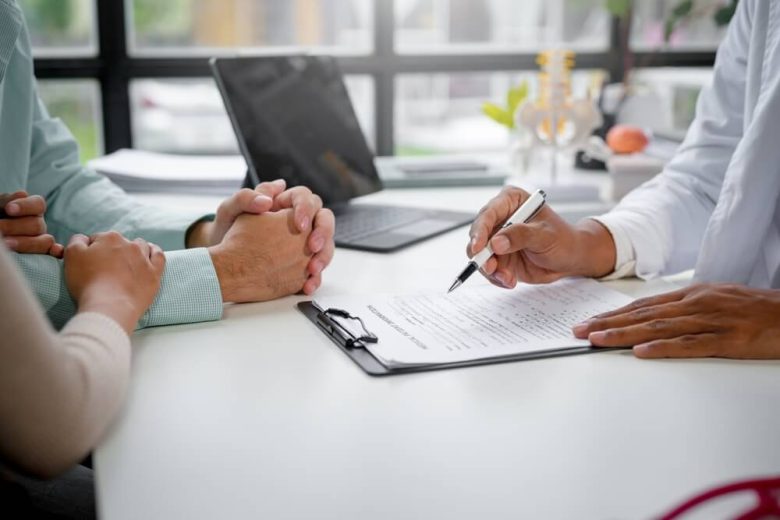 Pareja revisando opciones con un asesor sobre dos seguros de salud al mismo tiempo en California, explicando cómo funciona la coordinación de beneficios entre dos pólizas.