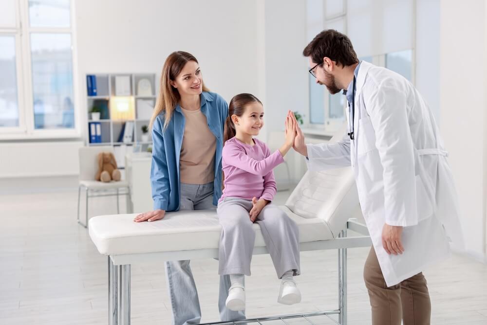 Madre y niña durante una consulta médica con dos seguros de salud al mismo tiempo en California, mostrando cómo la doble cobertura puede ayudar a reducir los gastos médicos.