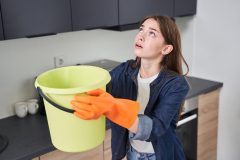 Mujer enfrenta una filtración en casa, relacionada con el seguro de hogar si una propiedad vecina daña tu casa.
