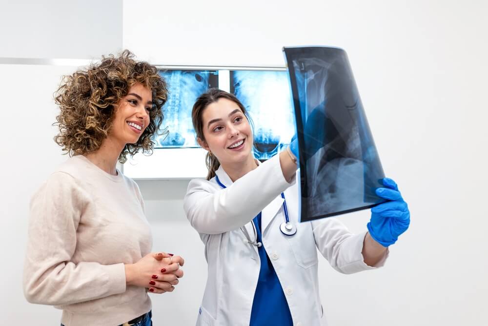 Doctora explicando una radiografía a una paciente durante una consulta médica.