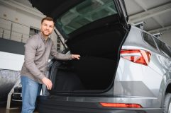 Hombre junto al maletero abierto de un SUV, relacionado con asegurar un auto usado comprado a un vendedor particular.
