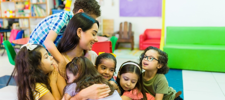 Niños hispanos abrazando a mujer voluntaria joven