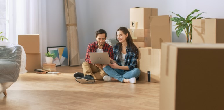 couple sitting in new apartment looking at renters insurance quotes at laptop