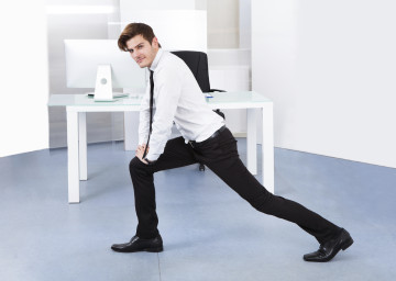 Portrait Of A Young Businessman Stretching In Office