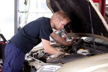A young mechanic under the hood of a car doing repairs