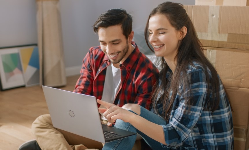 young couple in their apartment looking for renters insurance at laptop