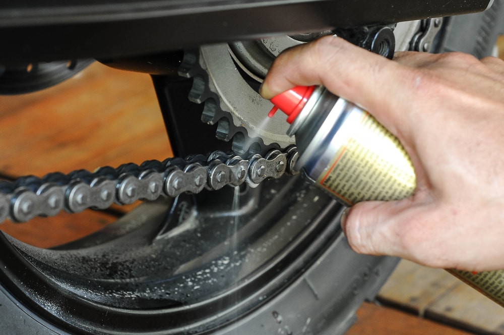 man keeping motorcycle chained lubed for maintance