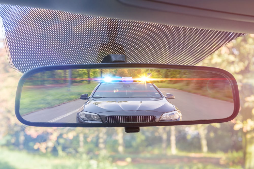 rearview mirror with a police car pulling the driver over