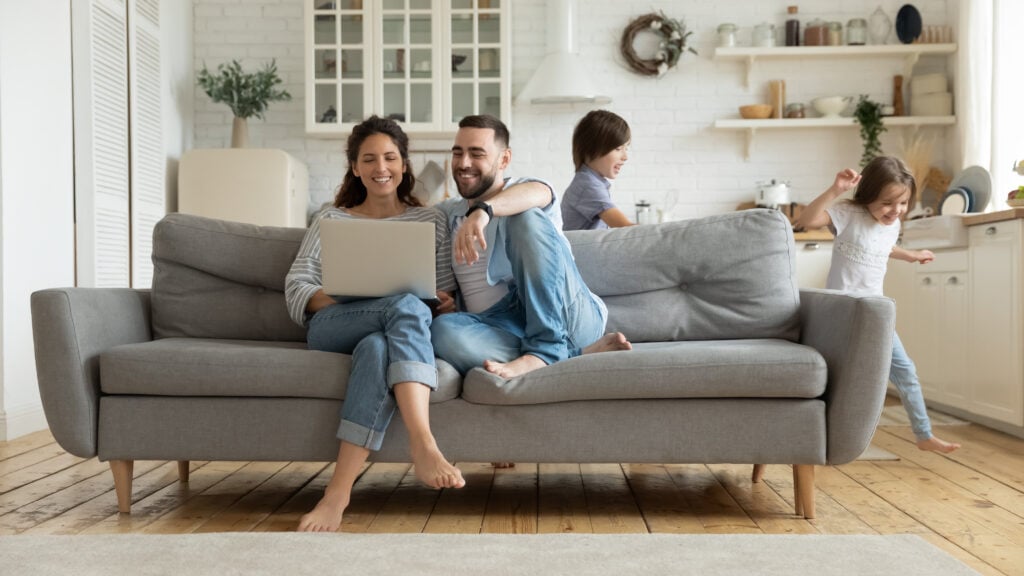 happy family in home with kids running and parents in couch looking for renters insurance