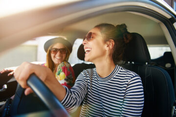 two happy young women in car driving around in california with insurance