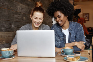 two happy women looking for car insurance in laptop
