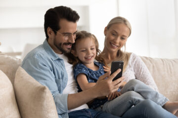 happy family with one child at couch looking at phone