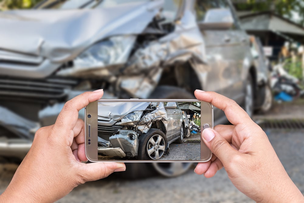 person taking a photo on phone of car accident damage