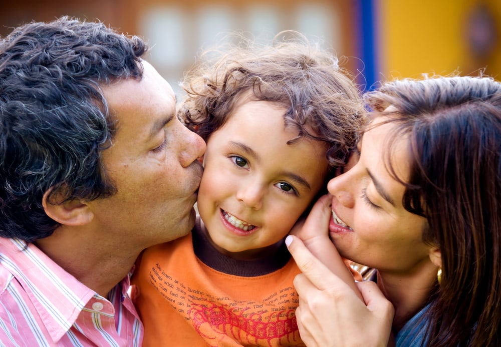 young family kissing child