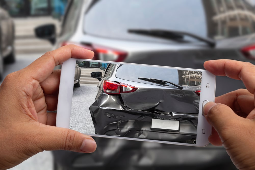 person taking photo of car in hit and run accident