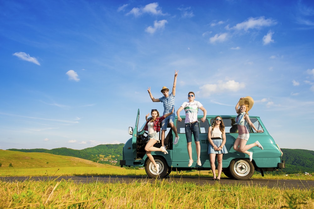 group of friends jumping in front of van on road trip