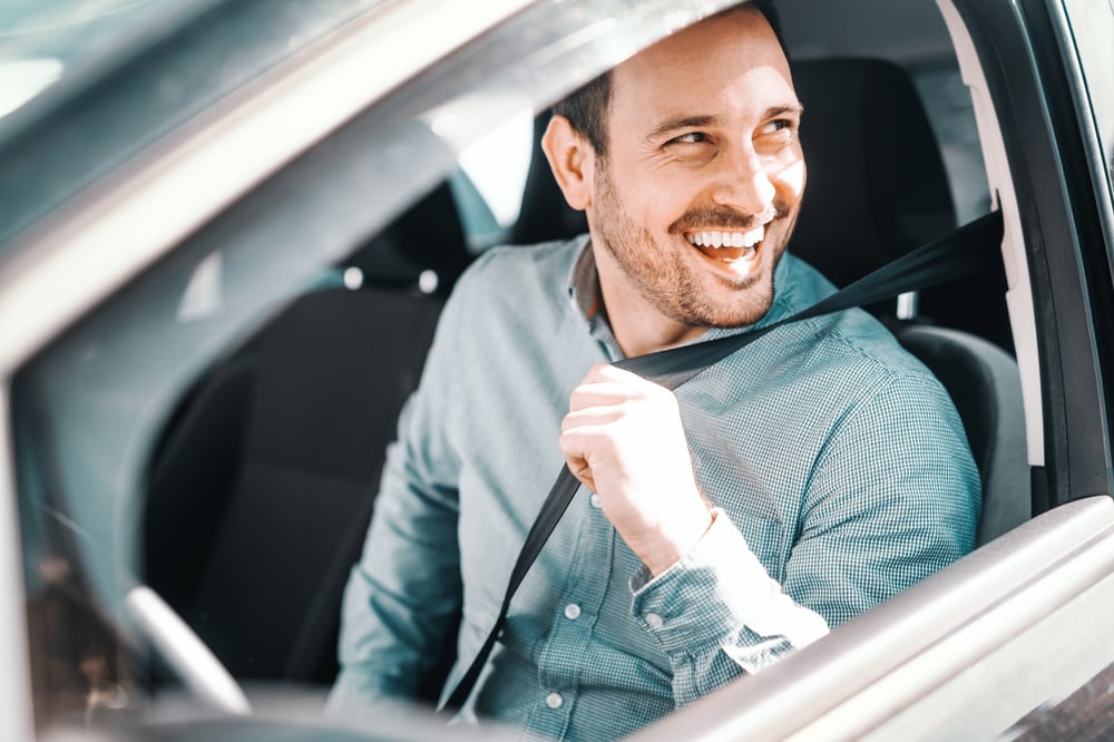 man smiling buckling seat belt in car