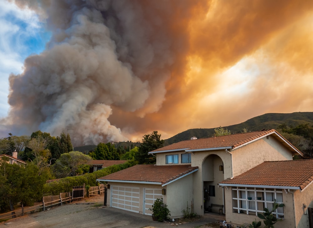 california wildfire burning in background of neighborhood