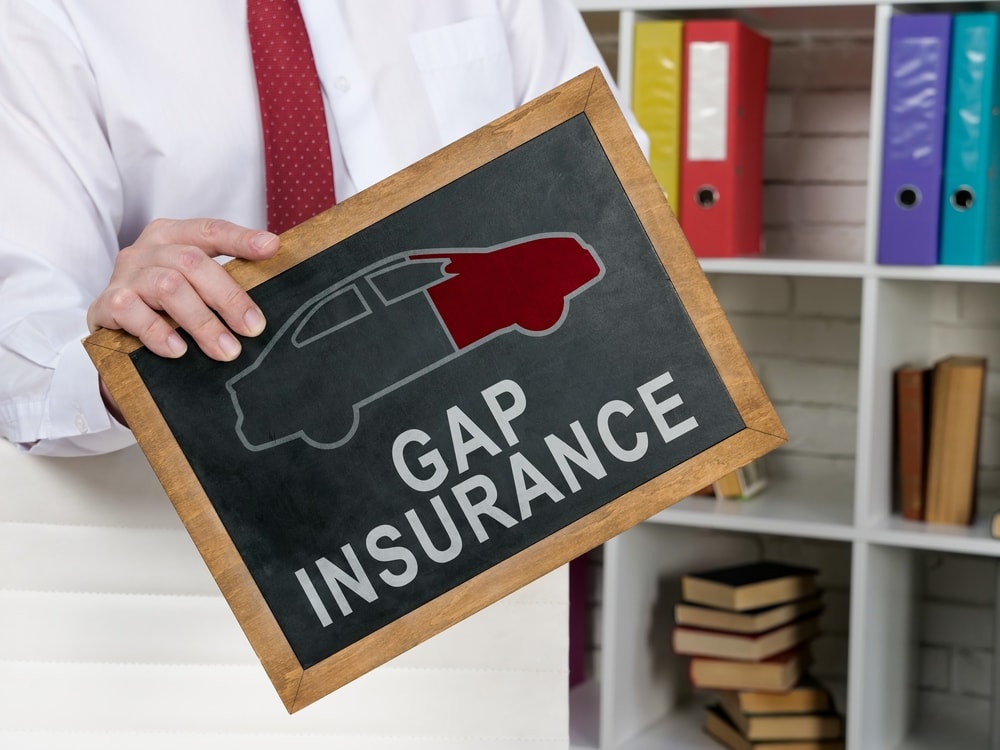 man holding blackboard with gap insurance written on it