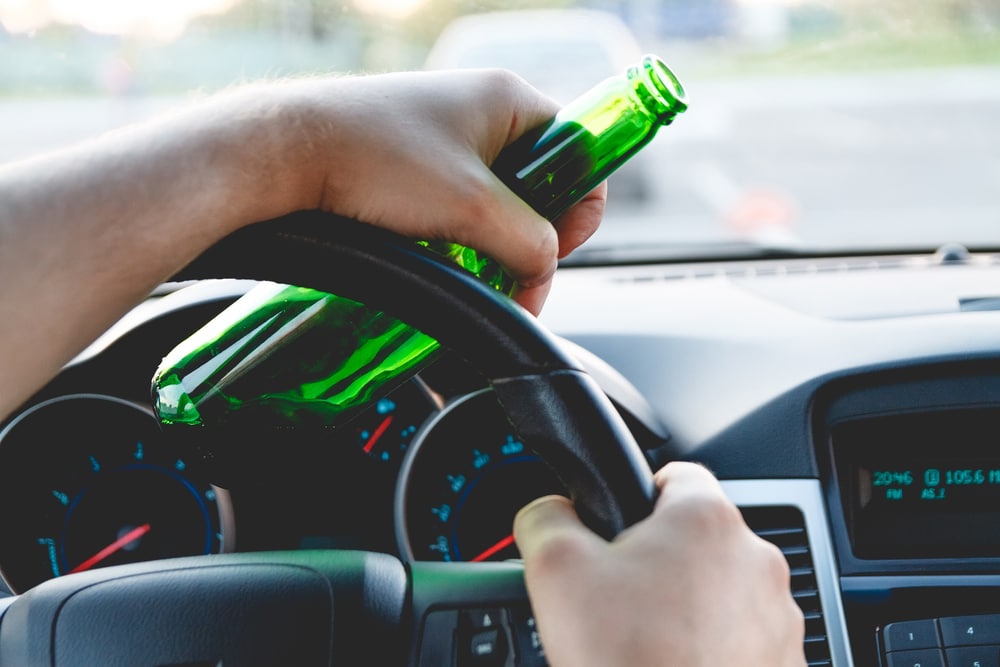 person holding beer bottle and steering wheel