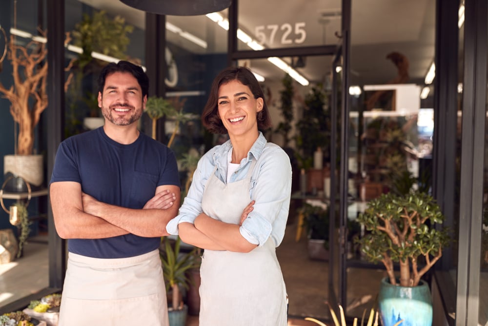 two small business owners standing outside of their shop