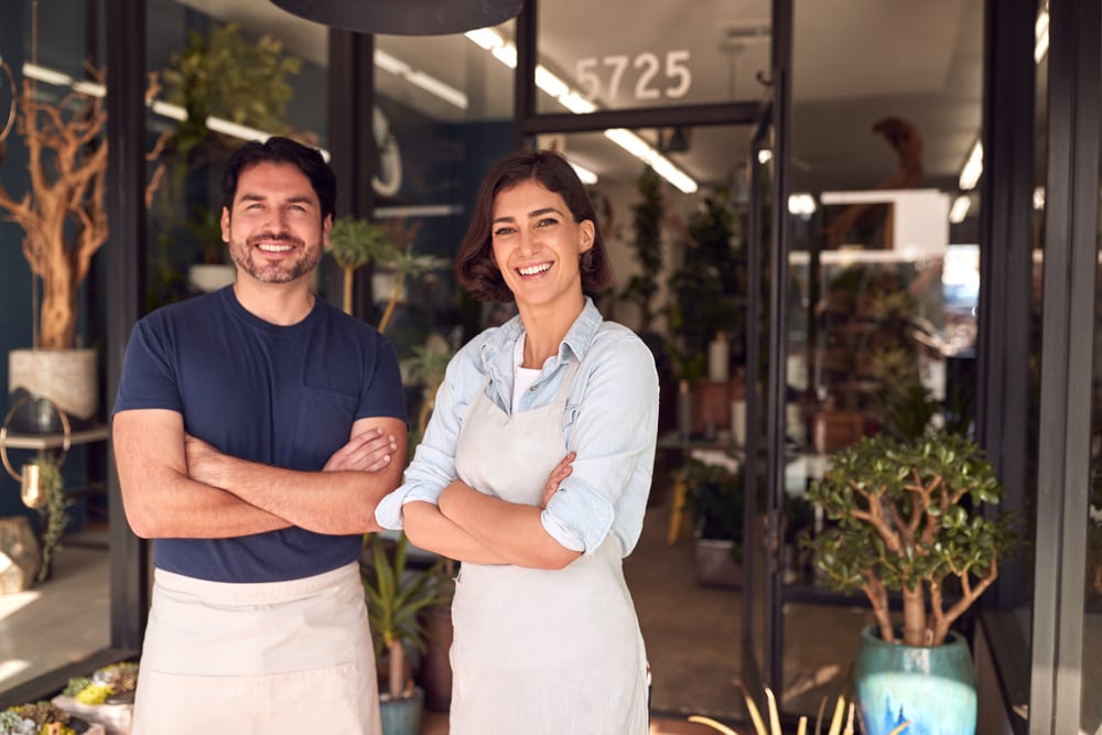 two small business owners standing outside of their shop