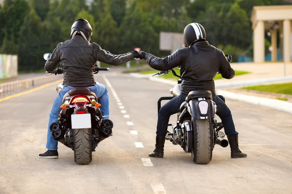 two motorcycle riders next to one another on road