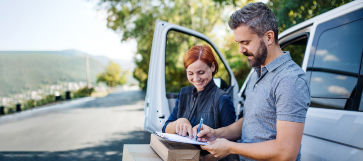 A woman delivering packages in a van, and a man signing for them.