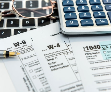 A pen and calculator on top of multiple W forms