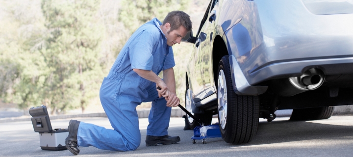 Man repairing the tire of a grey car